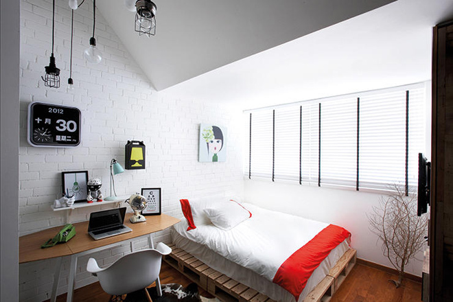 Kiểu giường gỗ pallet, bức tường gạch mộc sơn trắng cùng đèn treo tường ấn tượng tạo ra phong cách công nghiệp cho căn phòng.